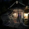 A themed setting presents 10-foot lighted black hanging skeleton ghost displayed outside a home, with the skull head, wide black gauze and long hanging silhouette clearly visible.
