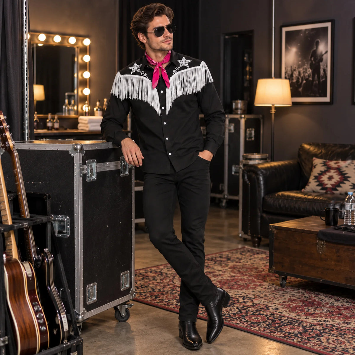 Man wearing the western fringe shirt and pink bandana beside a mirror guitar and backstage equipment.