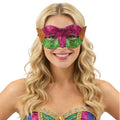 An adult wears a purple green and gold glitter Mardi Gras eye mask, with the purple, green and gold glitter panels with pointed side accents clearly visible.