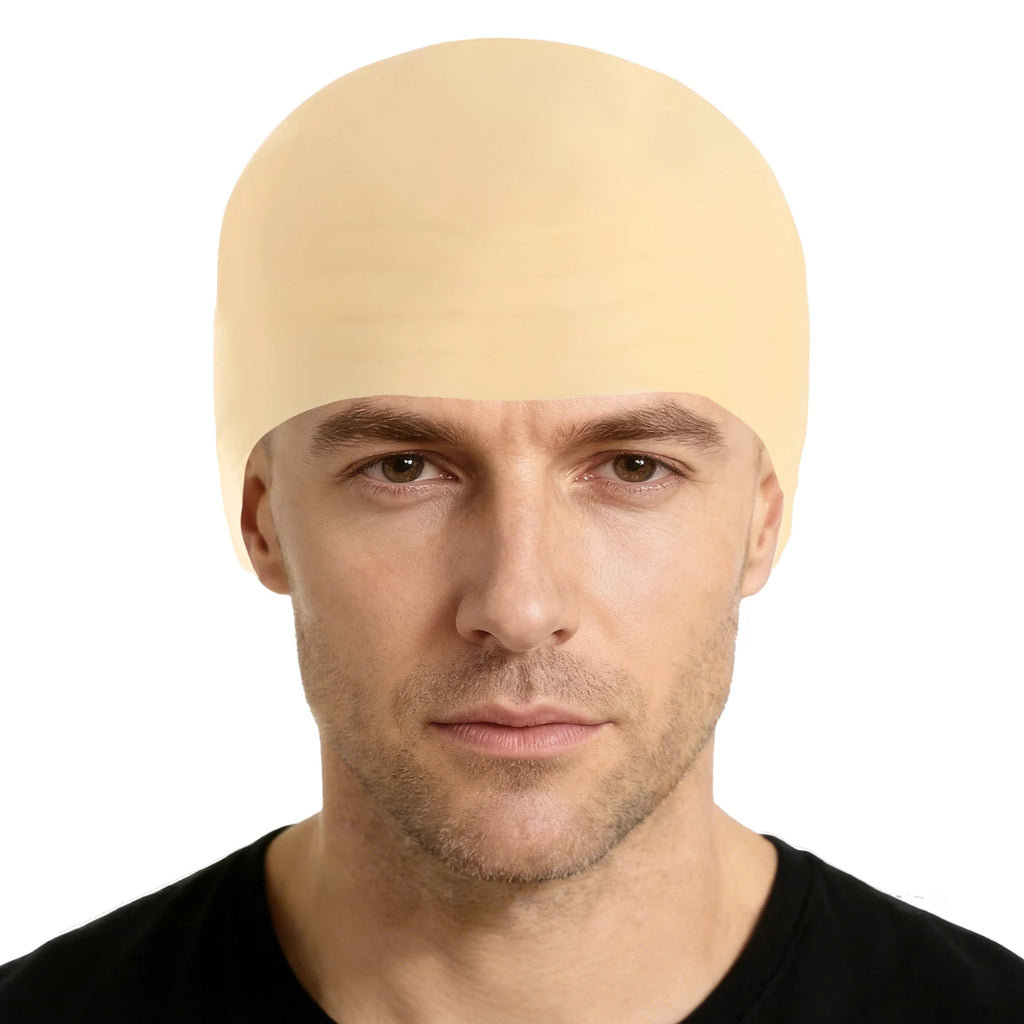 An adult wears a smooth bald cap costume accessory, with the smooth skin-tone surface and close-fitting cap shape clearly visible.