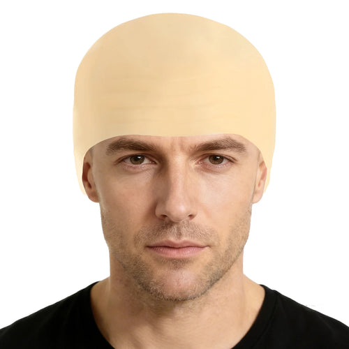 An adult wears a smooth bald cap costume accessory, with the smooth skin-tone surface and close-fitting cap shape clearly visible.