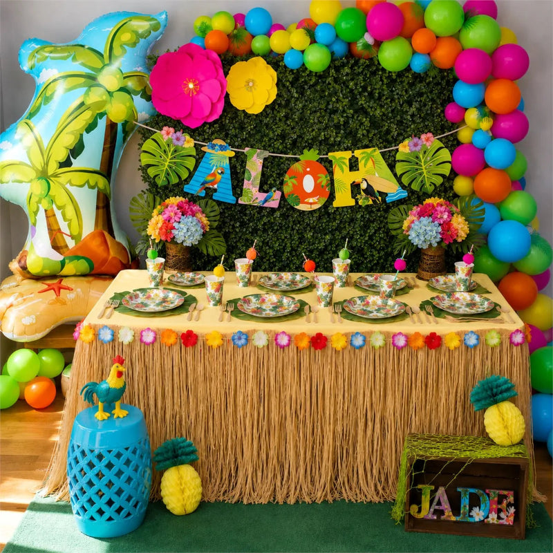 Aloha party table setup with a balloon garland, palm foil balloon, and tropical tableware