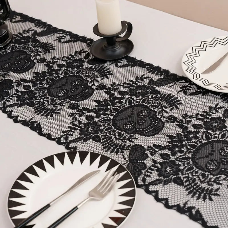 Close-up of a black lace Halloween table runner with skull pattern on a white dining table.