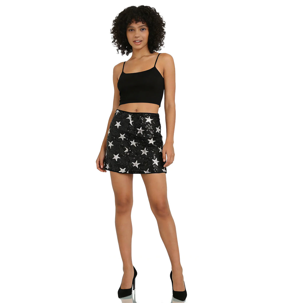 A woman models the black mini skirt with silver star sequins from the front against a white background, showing its overall silhouette.