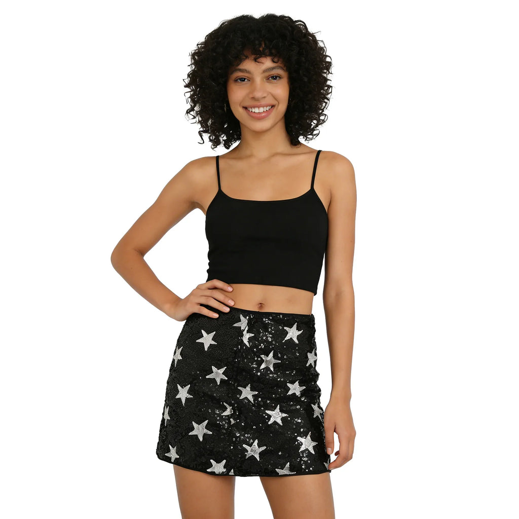 A woman models the black mini skirt with silver star sequins in a full-length front pose against a white background.