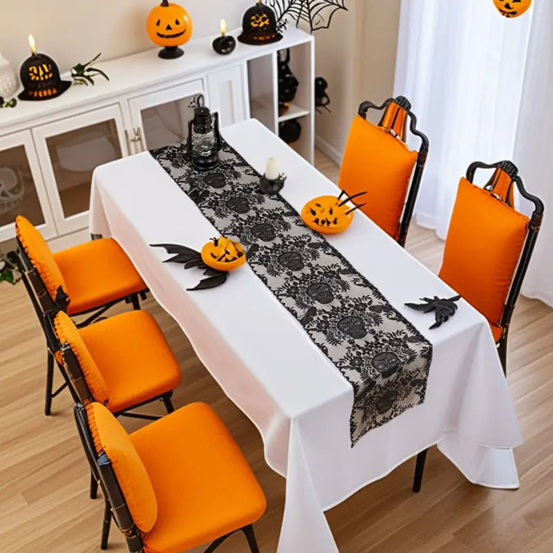Black skull lace Halloween table runner displayed on a white dining table with orange chairs and spooky decorations.