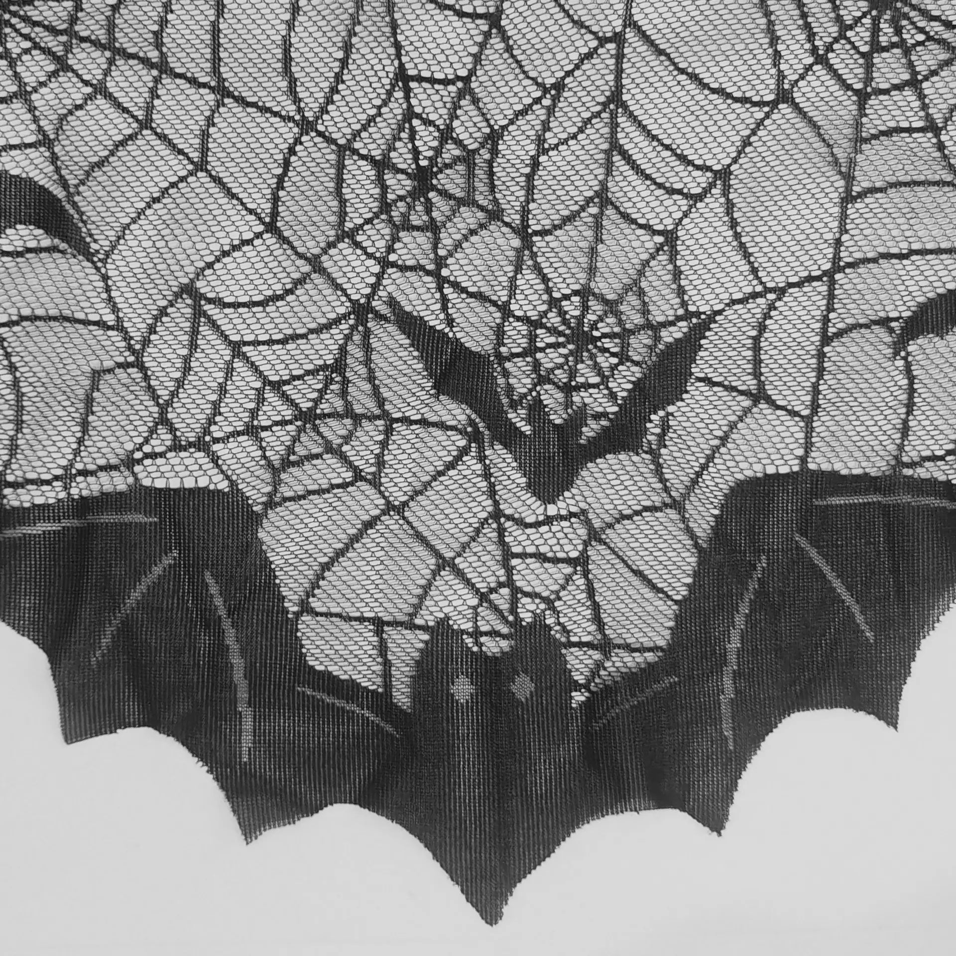 Detailed view of black spider web lace mantel scarf with bat and web pattern for Halloween decor