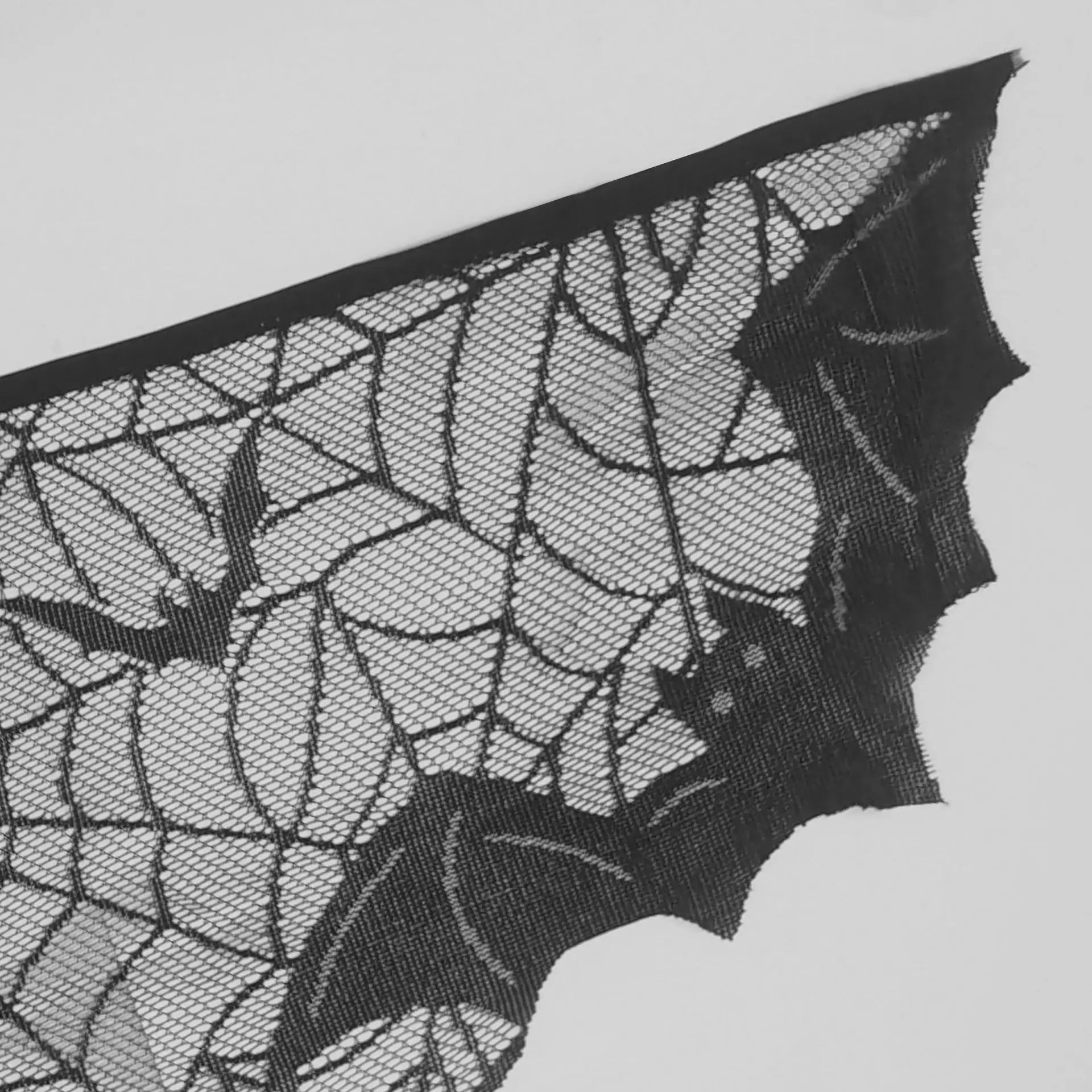Close-up of black spider web lace mantel scarf with bat-shaped edge detail
