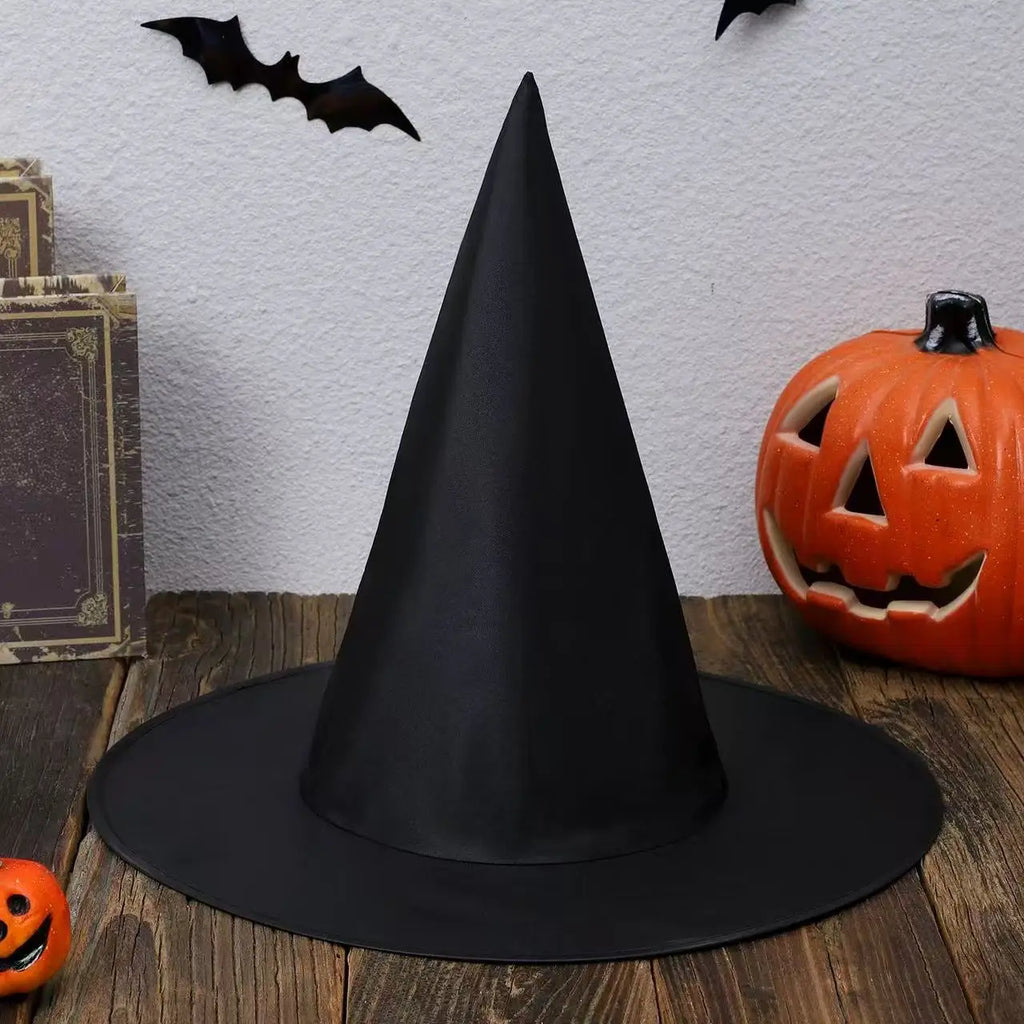 Black witch hat displayed with pumpkins, bats, books, and rustic Halloween decorations for spooky party styling.