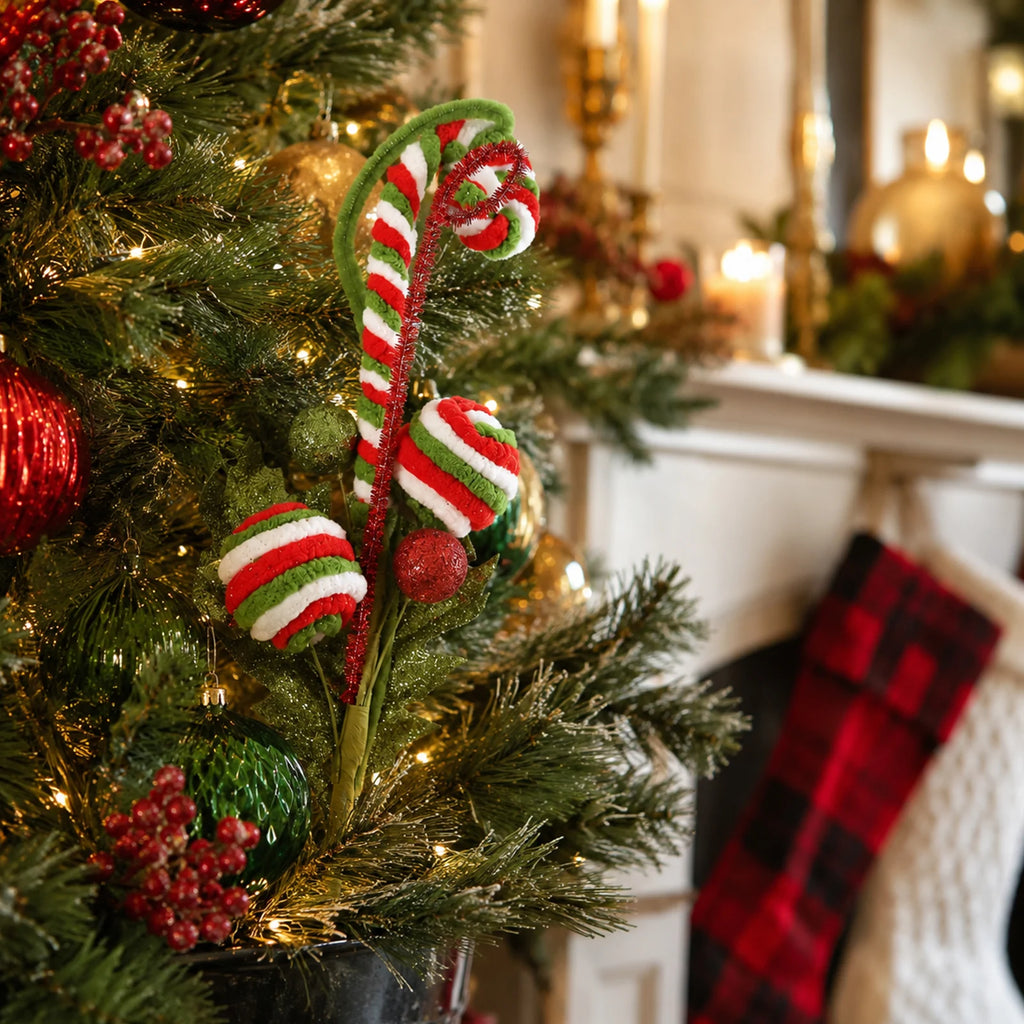 A red, green and white candy-style pick is tucked among decorated Christmas tree branches.
