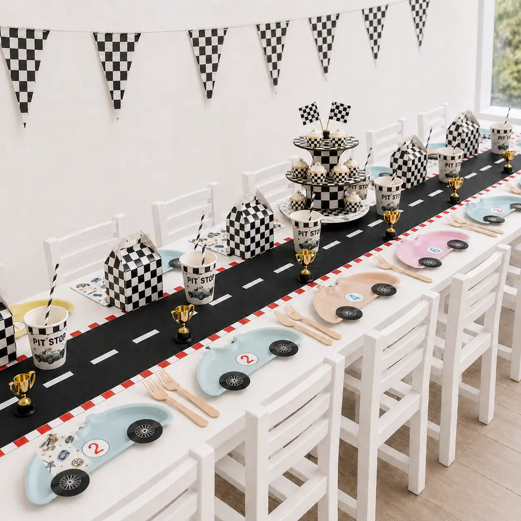 Checkered race car party table setup with car-shaped plates, wooden cutlery, pit stop cups and vintage race car napkins