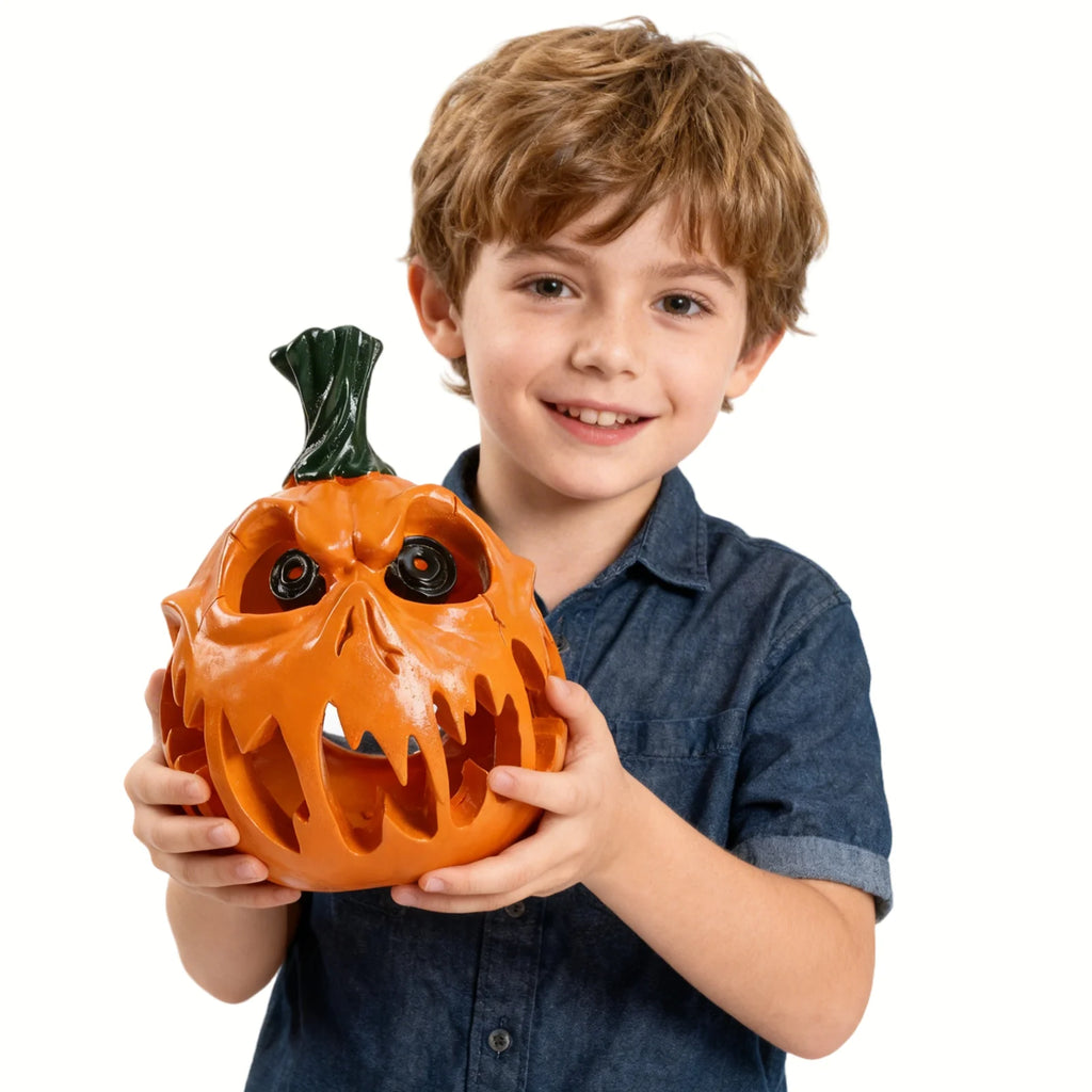 A child holds the orange demon pumpkin figurine against a white background, showing its fanged face and glossy finish.