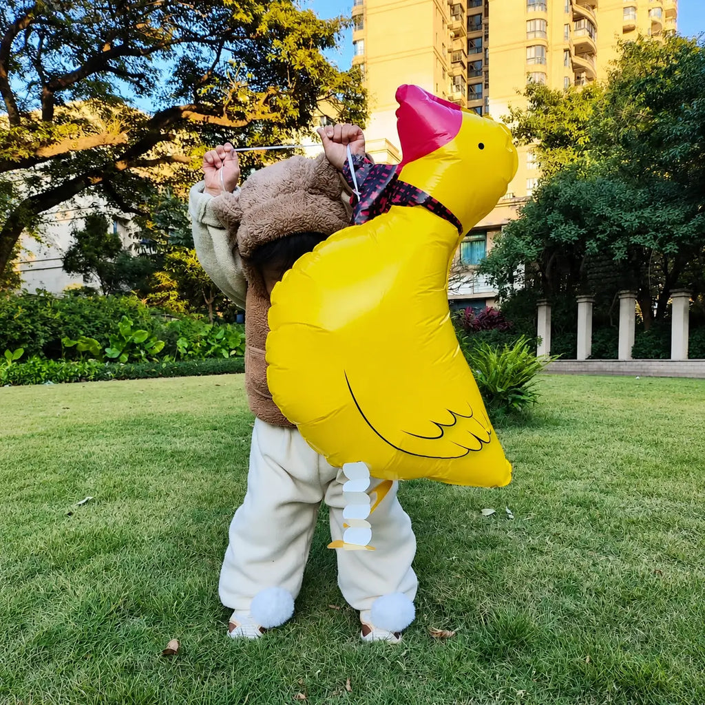 Child holding a large yellow duck-shaped foil balloon in an outdoor garden