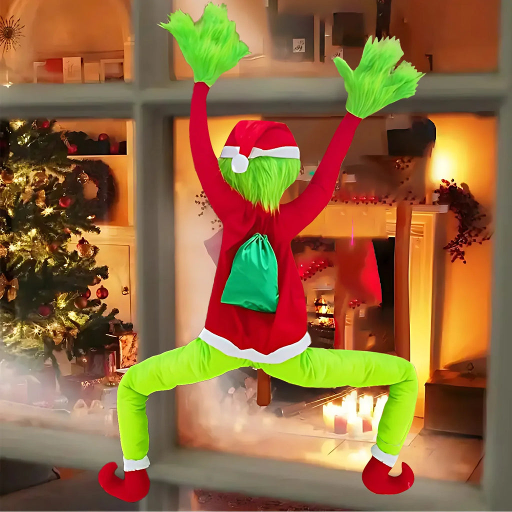 Green furry climbing Christmas character decoration (Inspired by the Grinch) climbing a lit window with green gift sack on its back