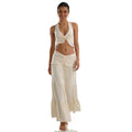 A woman models the cream halter top and maxi skirt set from the front against a white background, showing its overall silhouette.