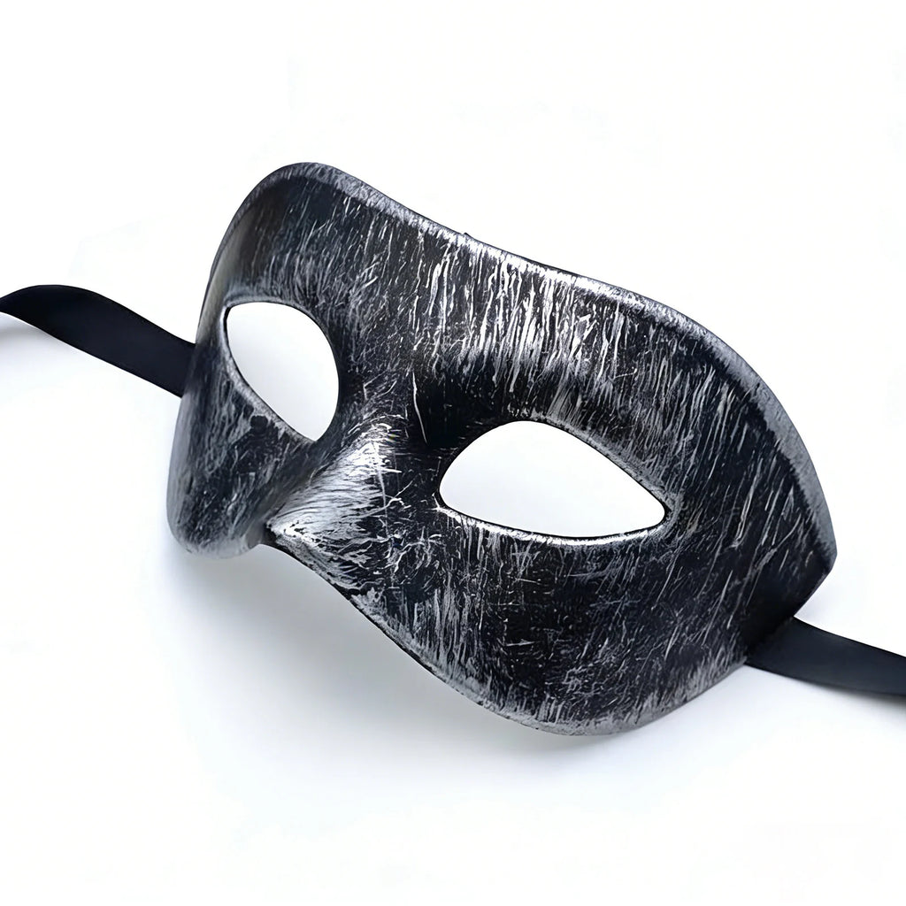 The distressed silver-black masquerade eye mask is shown from a low side angle, highlighting its sculpted shape and brushed finish.
