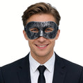 A clear product view presents a vintage black masquerade eye mask with distressed silver finish worn by an adult, with the sculpted eye shape and adjustable black ribbon tie clearly visible.