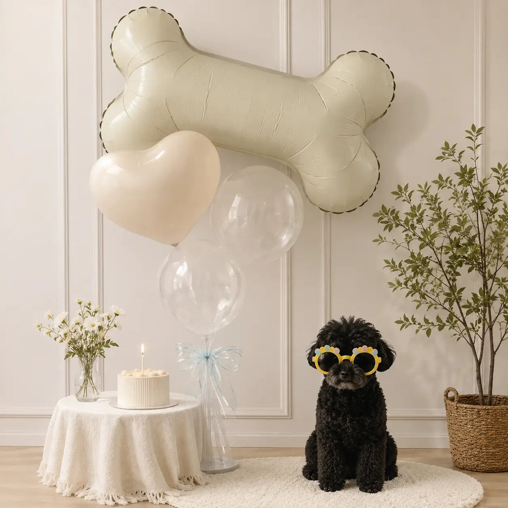 Dog bone balloon with heart balloons, clear balloons, birthday cake, and dog wearing party glasses for a pet birthday celebration.