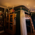 Floating LED candles hanging in a cozy bedroom with warm lights, dark curtains, bookshelves, and magical room decorations.