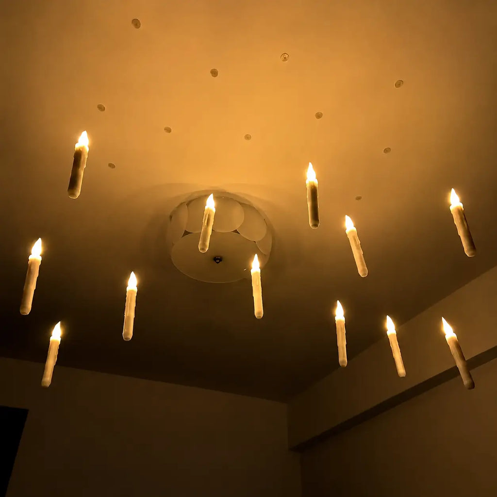 Warm glowing floating LED candles hanging from a ceiling for magical room, Halloween party, and themed event decorations.