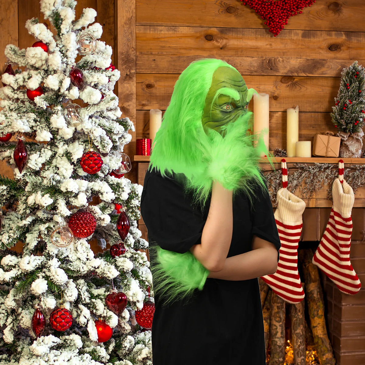 A model wears the green monster mask beside a decorated Christmas tree. This hatless style has long green hair.