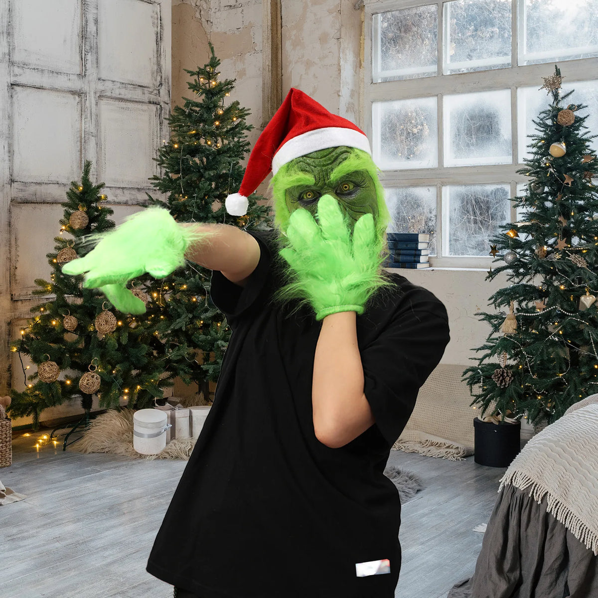 A model wearing the green monster mask reaches toward the camera in a Christmas room. This style has a wrinkled face and red hat.