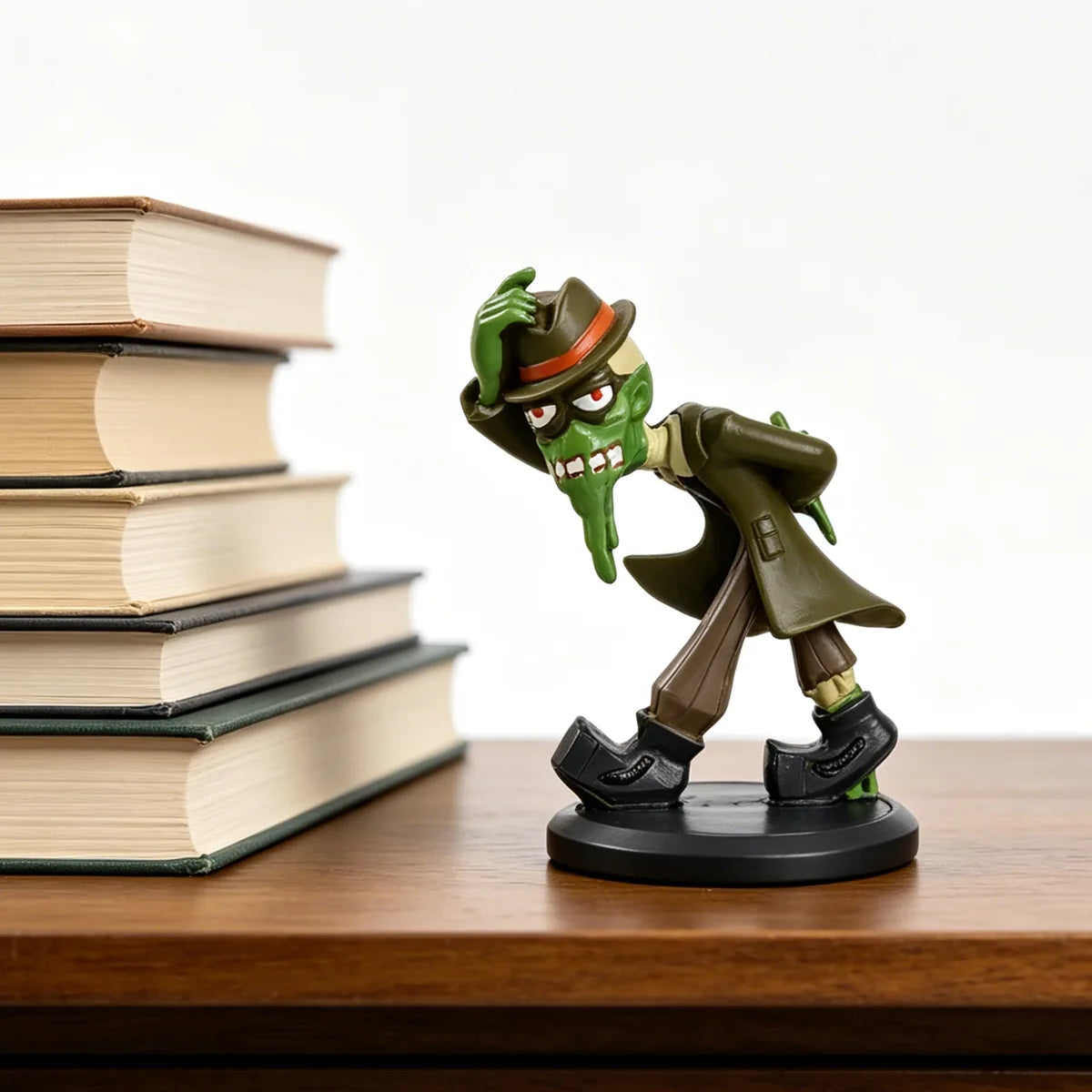 Green mud monster figurine displayed beside books to show scale.