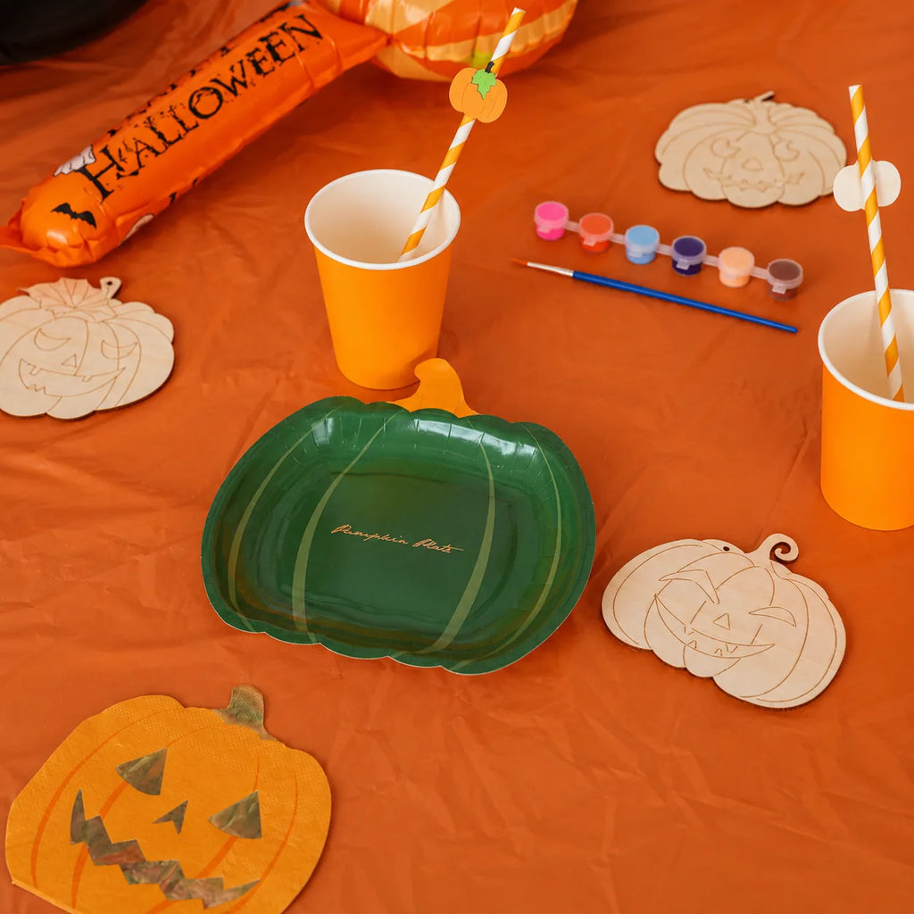 Green pumpkin plates with orange cups, pumpkin straws, wooden pumpkin ornaments, paint set and Halloween party tableware
