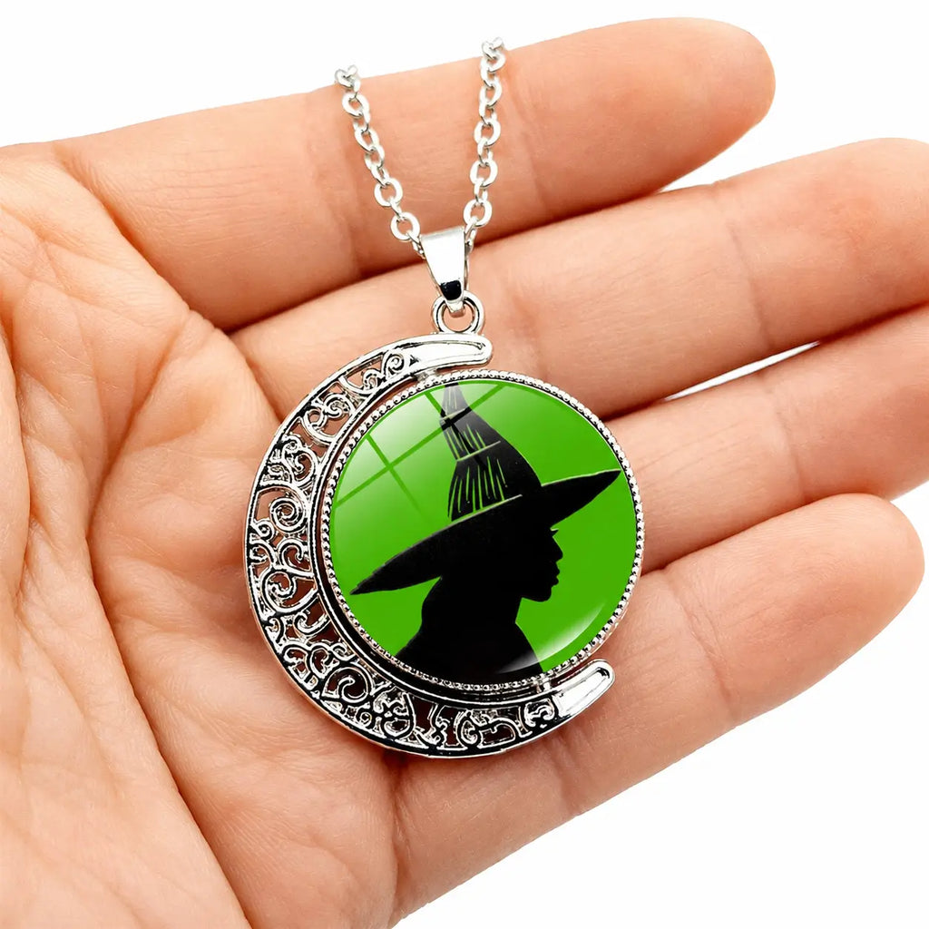 Green witch moon pendant necklace displayed in hand with silver chain and detailed crescent frame.