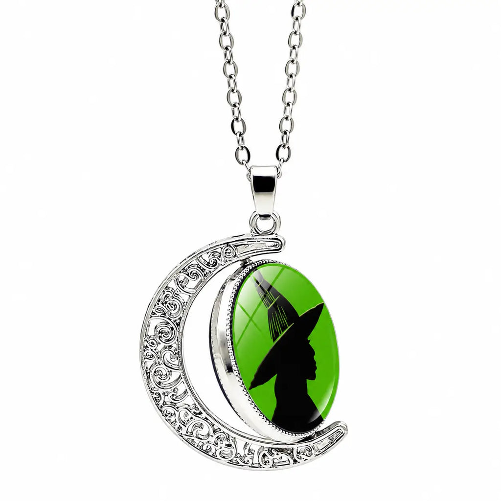 Silver moon pendant necklace with green witch silhouette charm and chain on a white background.