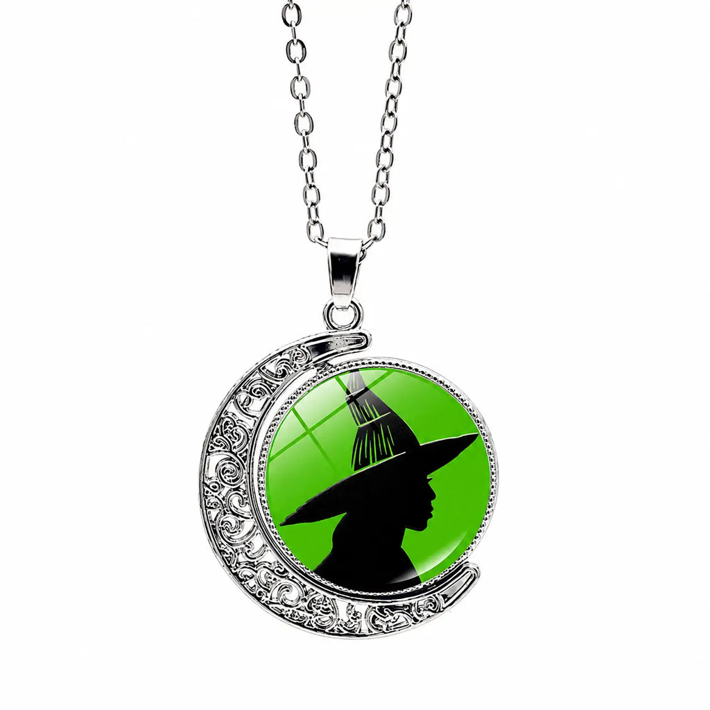 Silver crescent moon pendant necklace with green witch silhouette design and chain on a white background.