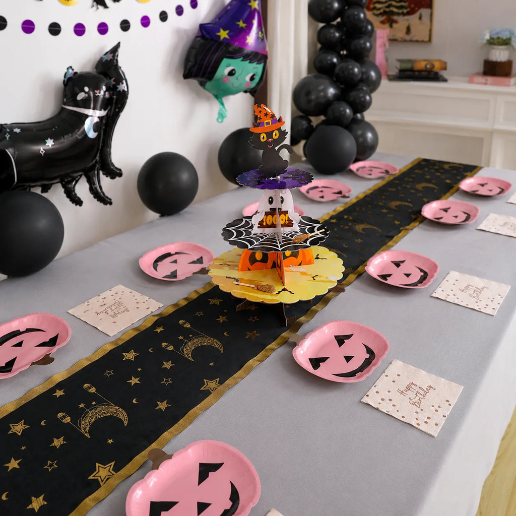 Halloween birthday table decorations with pink pumpkin plates, Happy Birthday napkins, black gold moon table runner and Halloween cupcake stand