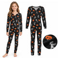 Child wearing black kids Halloween pajamas with orange pumpkins, white skeletons and mummy characters beside the matching one-piece garment.