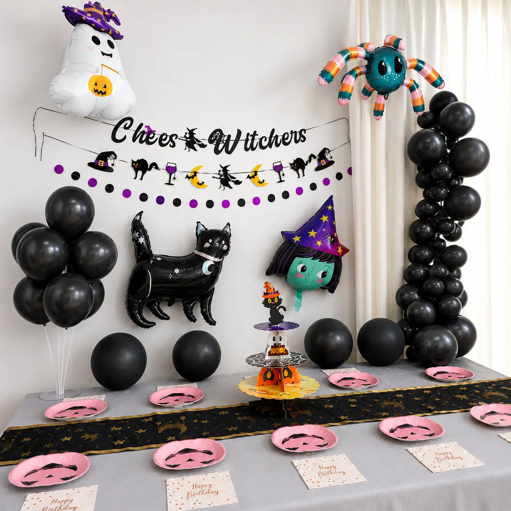 Little witch Halloween birthday party table setup with black balloon arch, witch banner, pink pumpkin plates, napkins and cupcake stand