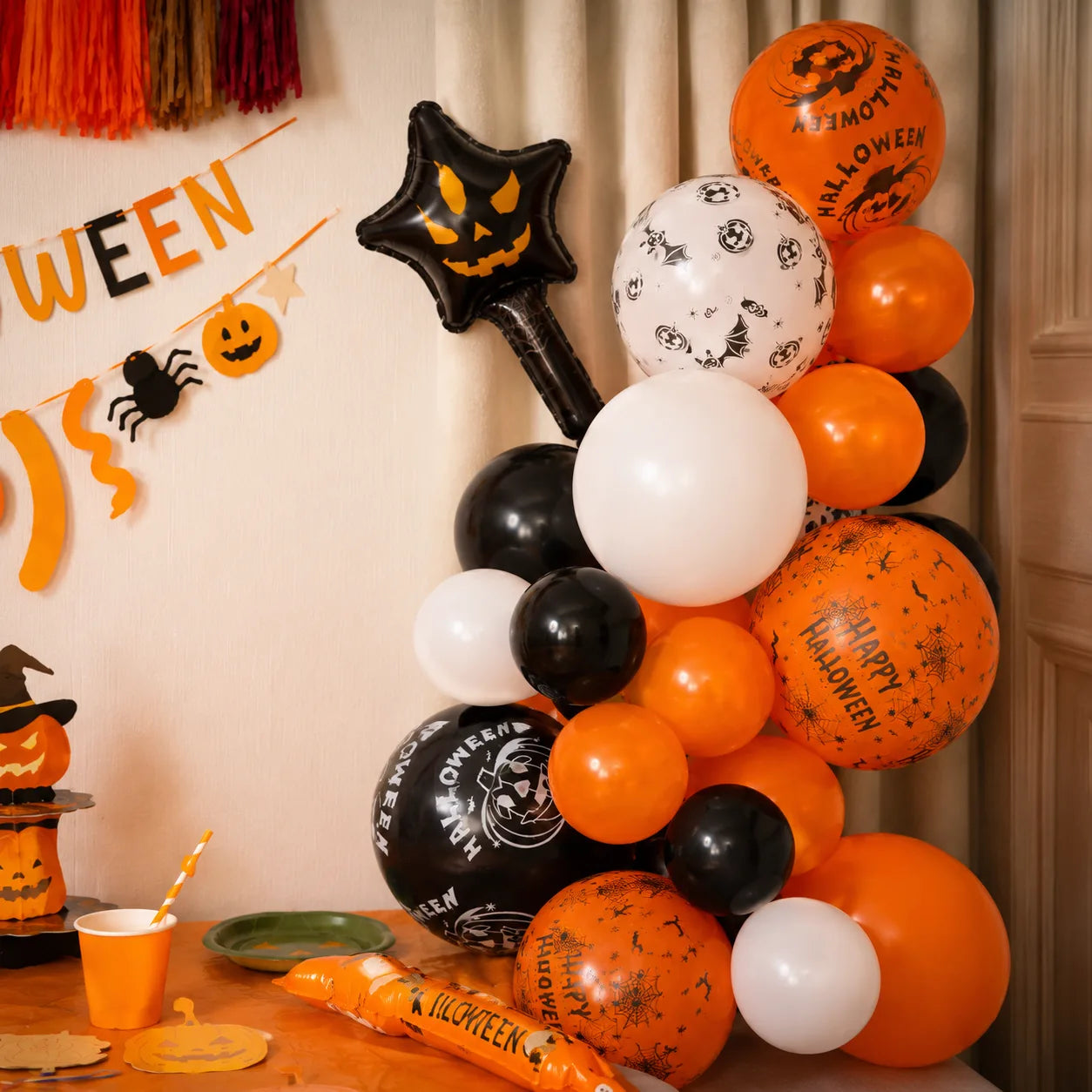 Orange and black Halloween balloon arch with printed pumpkin balloons, star foil balloon, tableware and pumpkin farm party decorations