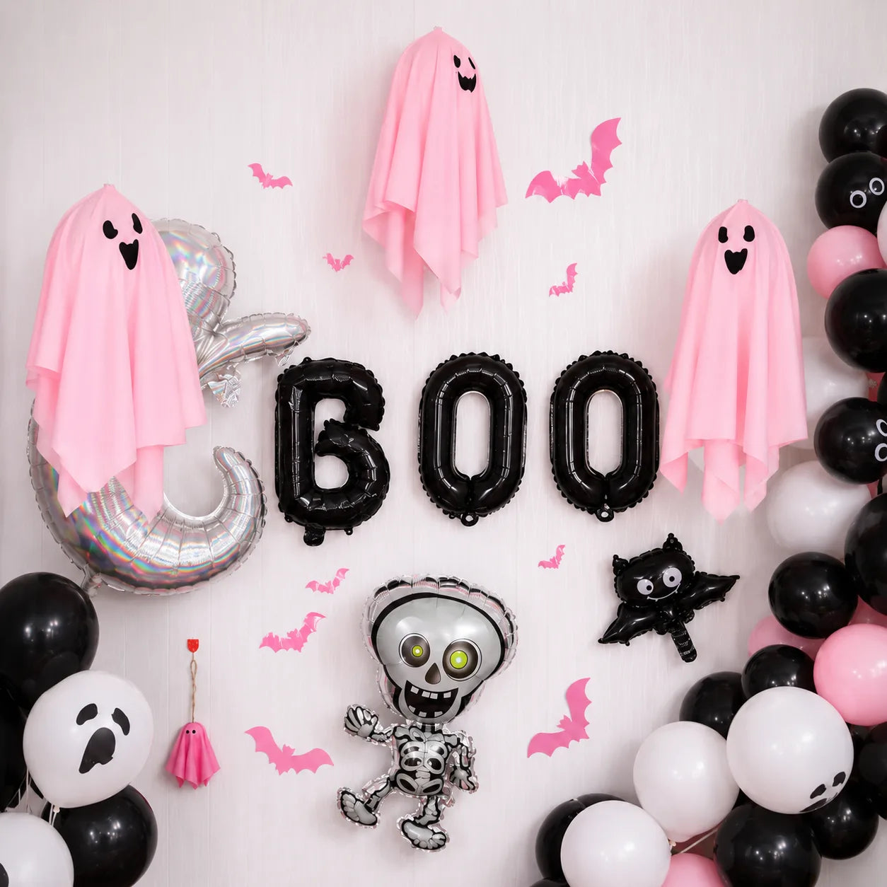 Pink Halloween balloon backdrop with hanging ghosts, bat decorations, BOO balloons and skeleton balloon