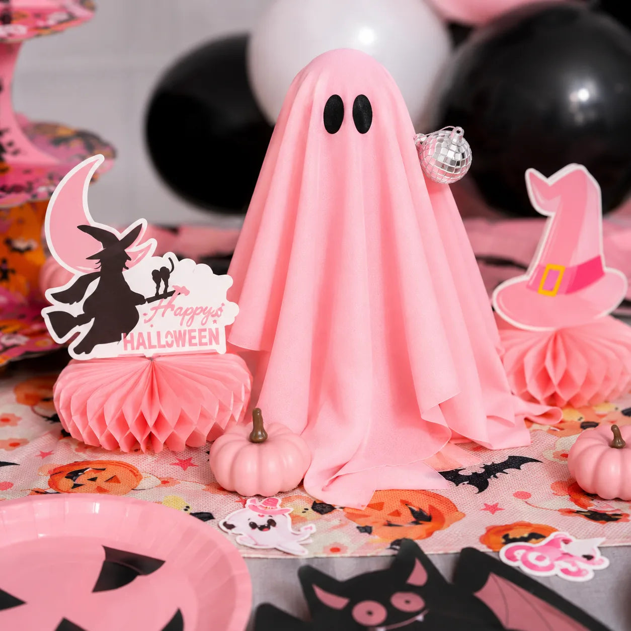 Pink light-up ghost decoration with mini pumpkins and Halloween honeycomb centerpieces