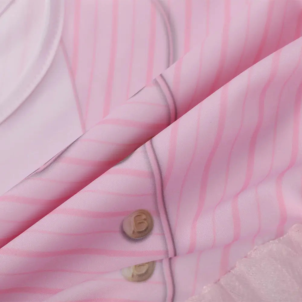 Close-up of pink princess dress fabric with striped sleeve, decorative button details, and soft tulle skirt texture.
