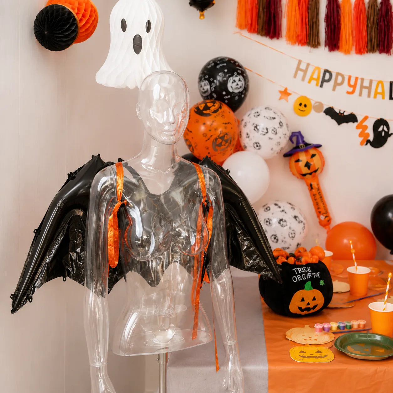 Pumpkin farm Halloween party decorations with orange tableware, balloons, hanging ghosts and harvest-inspired pumpkin accents