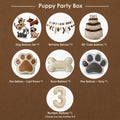 Puppy party box contents with dog balloon set, happy birthday banner, cake balloon, paw balloons, bone balloon, and number balloon for dog themed birthday decorations.