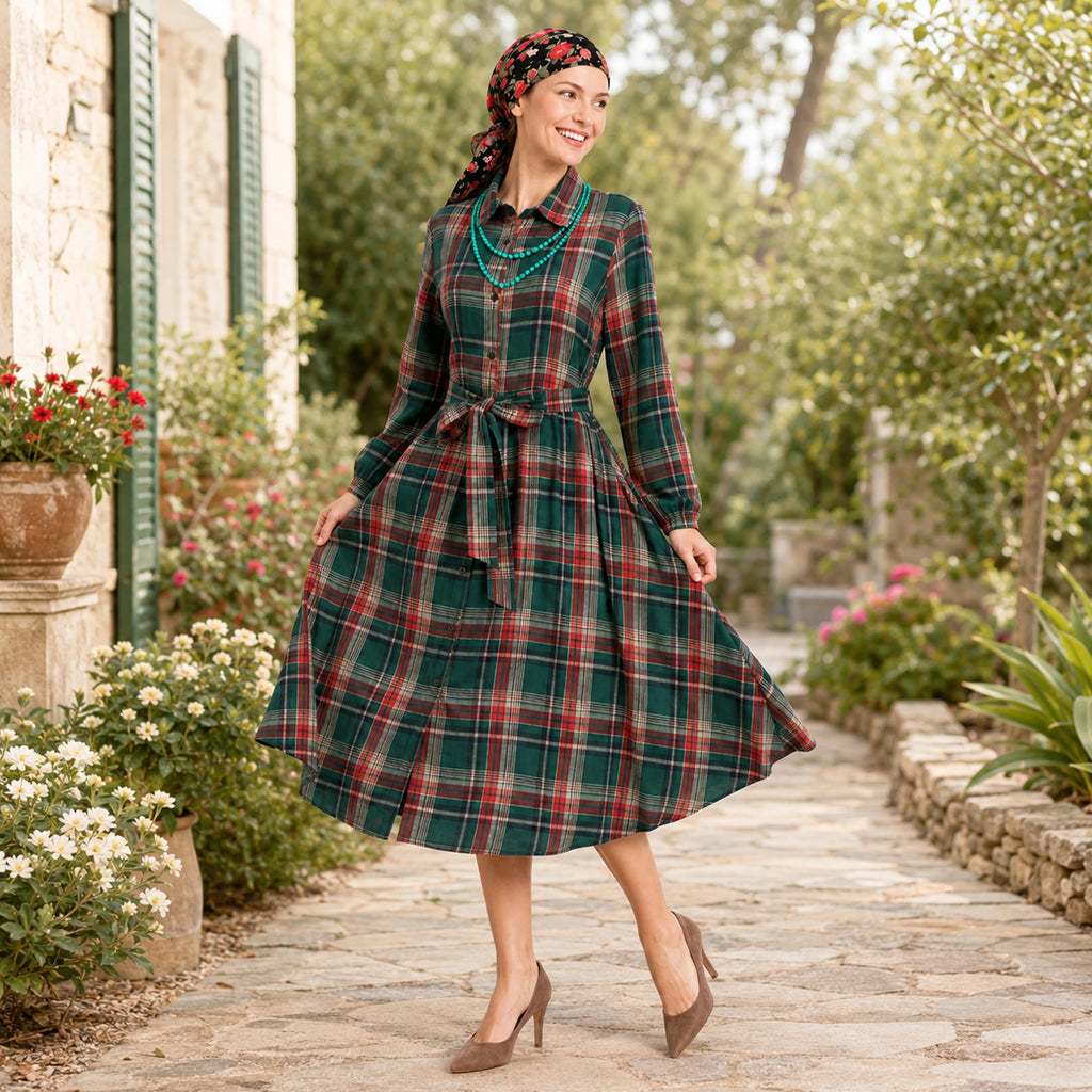 Woman wearing the red and green plaid dress with its matching belt in a garden setting.