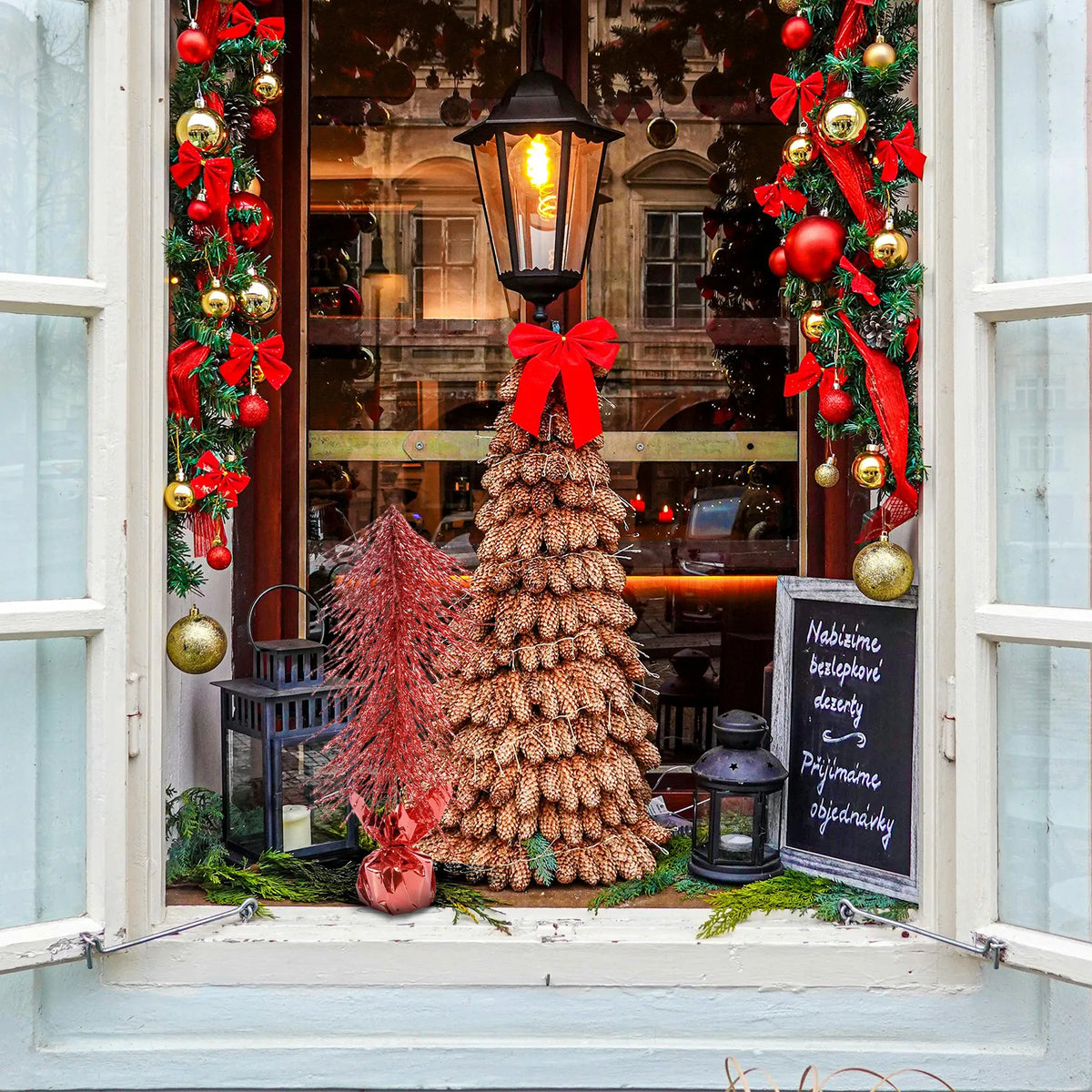 A red tabletop Christmas tree appears beside other decorations in a shop window.