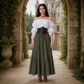 Renaissance fair outfit with olive green maxi skirt posed on stone steps
