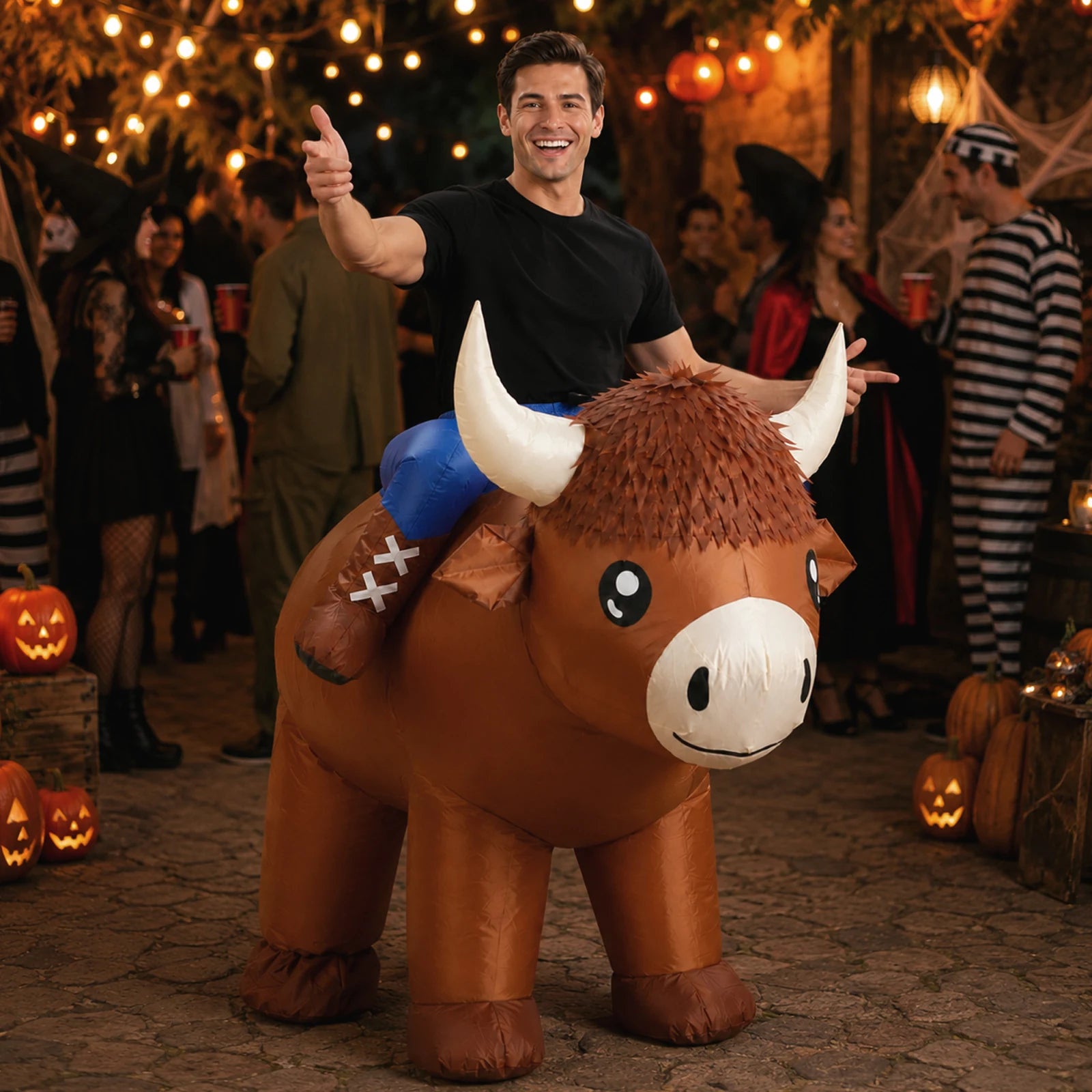 An adult wears the inflatable Highland cow costume at a lively outdoor backyard party.