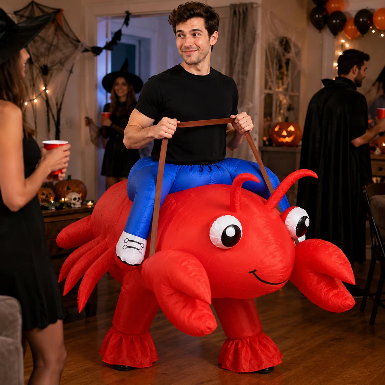 An adult wears the bright red inflatable lobster costume among friends at a house party.