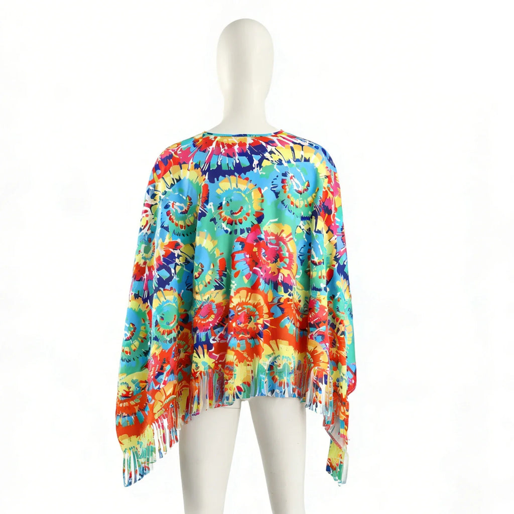 The back mannequin view shows the round neckline, multicolor print placement, wide silhouette and fringed lower edge of the poncho.