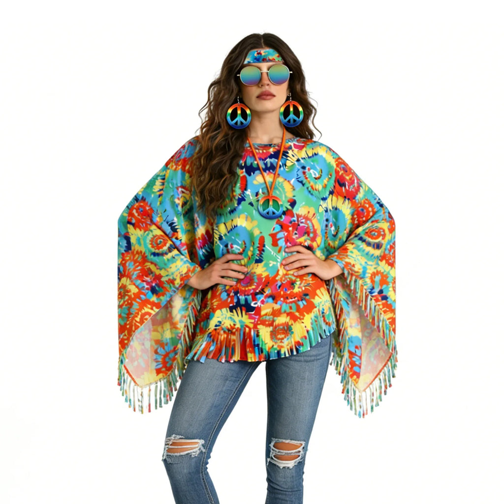 The hands-on-hips pose shows the poncho's wide draped sides, asymmetric points and long fringe against a white background.