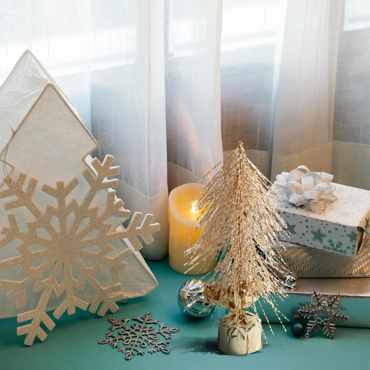 A gold tree sits among a gift box and other winter decorations.