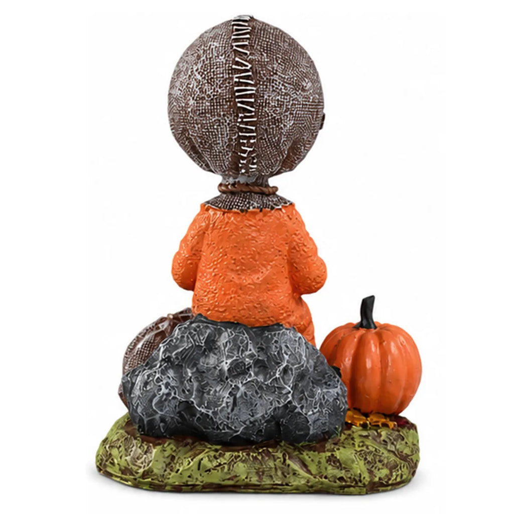 Back view of the trick-or-treat child figurine shows the stitched head, rock seat, and textured base.