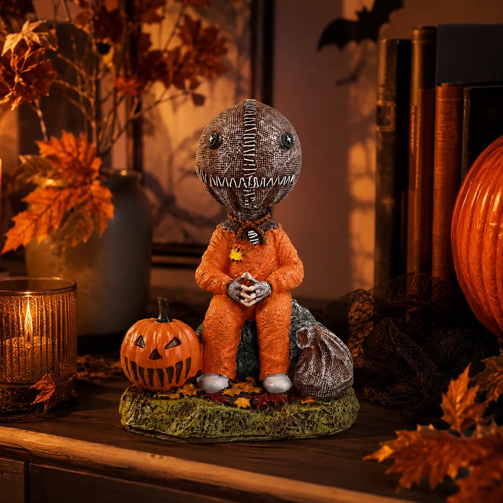 Trick-or-treat child figurine displayed beside candles, pumpkins, books, and seasonal decor.